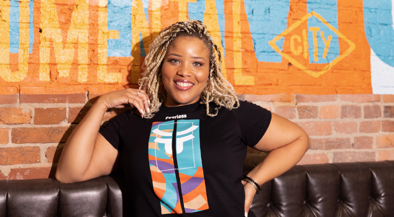Female model against painted brick mural with fearless anniversary shirt
