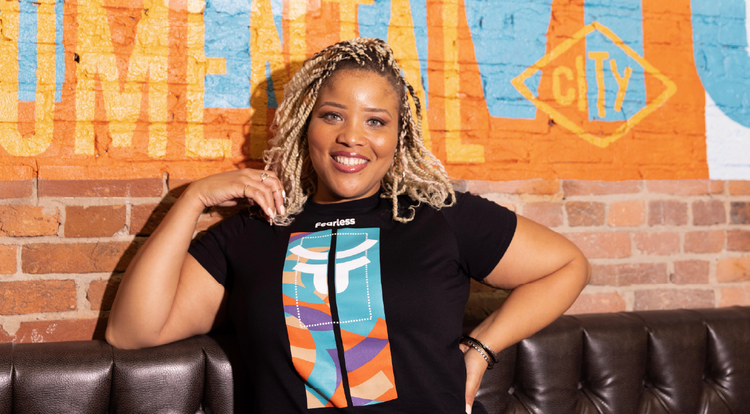 Female model against painted brick mural with fearless anniversary shirt